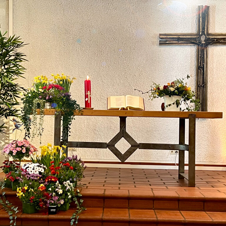 Ein Altarraum einer Kirche mit Blumenschmuck.