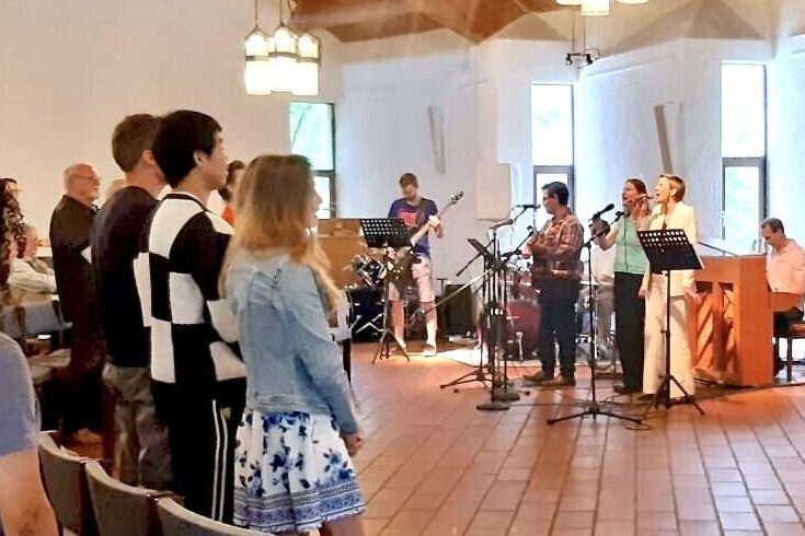 Eine Band spielt in einer Kirche. Die Gäste singen mit.