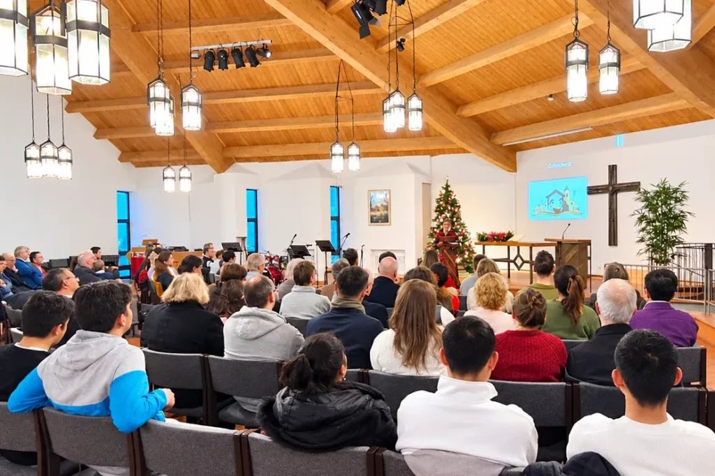 Gottesdienst an Weihnachten. Menschen von hinten die einer Predigt zuhören.